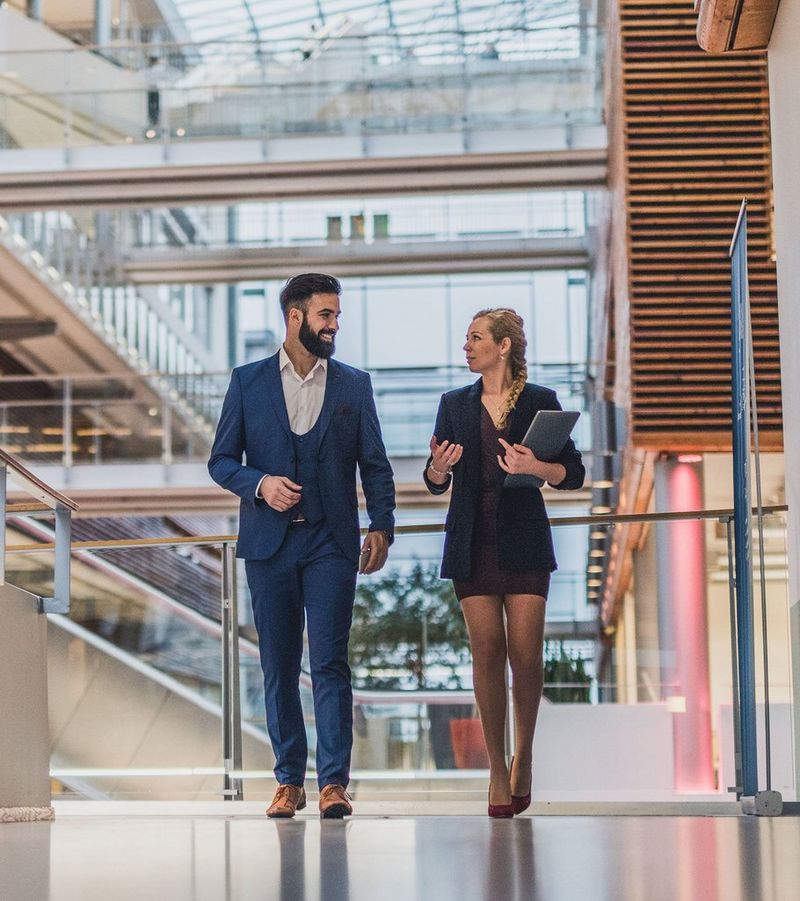 Women in stripy shirt sits in a brown leather chair while resting her legs on the desk beside a laptop as she reads a document.